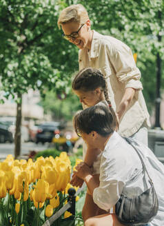 Lesbisches Paar mit Tochter kauft gelbe Tulpen in einem Geschäft - VSNF01004