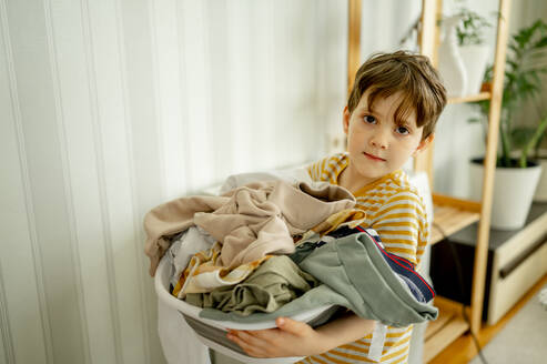 Junge mit schmutziger Kleidung im Wäschekorb zu Hause - ANAF01508