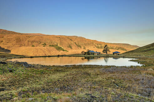 Hütten am See vor einem Berg in Lotheni, KwaZulu-Natal, Drakensberge, Südafrika - ANSF00390