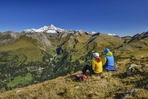 Mann und Frau sitzen auf einem Berg im Nationalpark Hohe Tauern, Österreich - ANSF00416