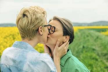 Liebendes lesbisches Paar küsst sich im Rapsfeld - VSNF01015