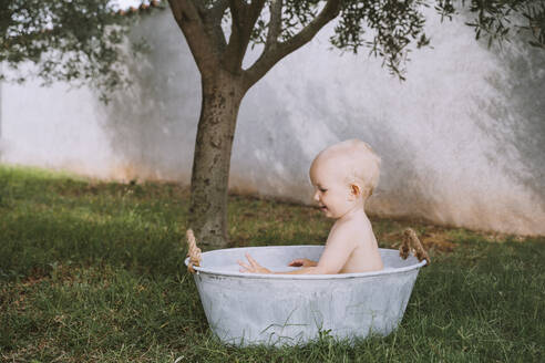 Kleiner Junge badet in der Wanne im Hinterhof - NDEF00717