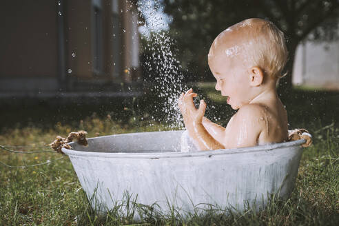 Kleiner Junge genießt in der Badewanne im Hinterhof - NDEF00725