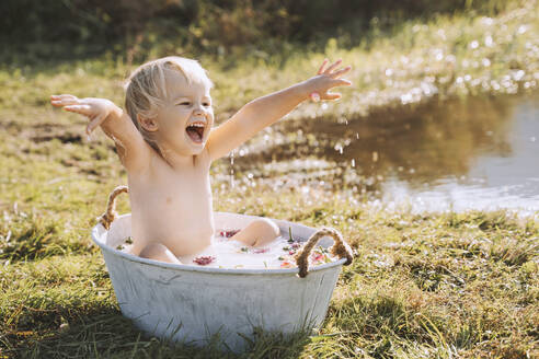 Verspieltes Mädchen nimmt ein Bad in der Wanne am See - NDEF00726