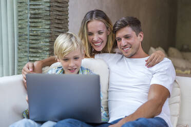 Happy family using laptop together at home - IKF00745