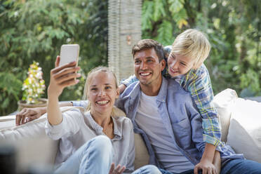 Happy woman taking selfie with family at home - IKF00770