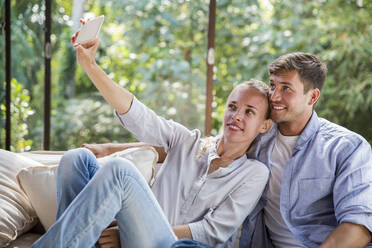 Young man with woman taking selfie at home - IKF00772