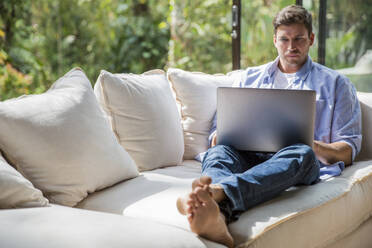 Serious freelancer working on laptop at home - IKF00787