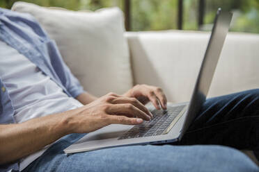 Hände eines Freiberuflers beim Tippen auf einem Laptop zu Hause - IKF00794