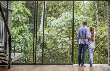 Couple standing by glass door at home - IKF00797