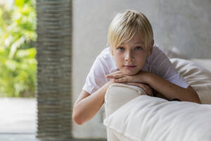 Blond boy lying on sofa at home - IKF00807