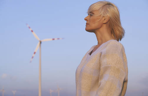 Kontemplative Frau in der Nähe einer Windkraftanlage in der Wüste - AZF00531