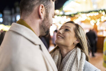 Smiling man and woman enjoying at Christmas market - WPEF07360