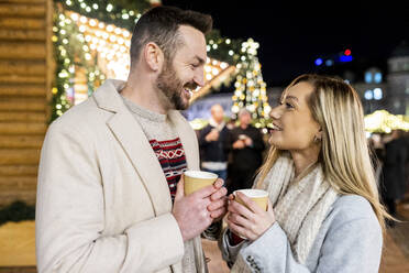 Glücklicher Mann und Frau mit Kaffeetasse auf dem Weihnachtsmarkt - WPEF07364