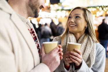 Lächelnde Frau und Mann mit Kaffeetasse auf dem Weihnachtsmarkt - WPEF07365