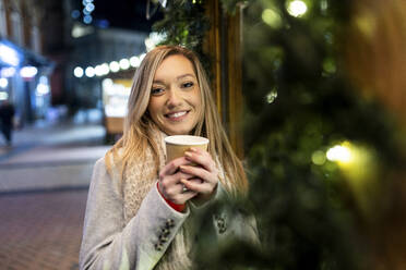 Glückliche junge Frau mit Kaffeetasse auf dem Weihnachtsmarkt - WPEF07378