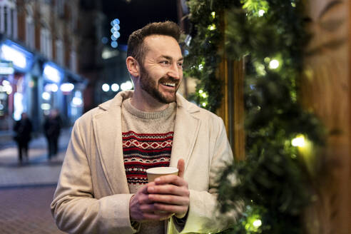 Glücklicher Mann mit Kaffeetasse auf dem Weihnachtsmarkt - WPEF07379