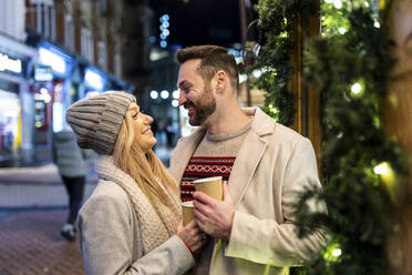 Happy couple standing with coffee cup at Christmas market - WPEF07380