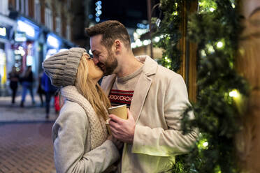 Glückliches Paar, das sich auf dem Weihnachtsmarkt küsst und umarmt - WPEF07381