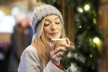 Lächelnde Frau mit Kaffeetasse auf dem Weihnachtsmarkt - WPEF07383