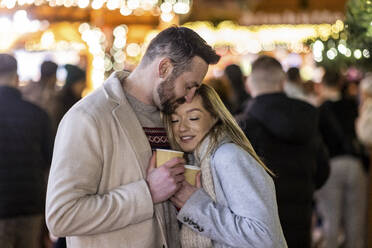 Loving couple hugging each other with coffee cup at Christmas market - WPEF07385