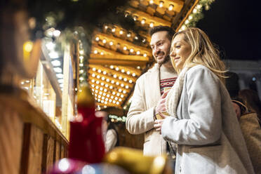 Glückliche junge Frau und Mann beim Einkaufen auf dem Weihnachtsmarkt - WPEF07390