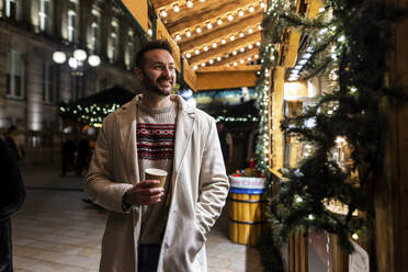 Man with coffee cup standing at Christmas market - WPEF07393