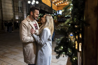 Glücklicher Mann und glückliche Frau stehen zusammen auf dem Weihnachtsmarkt - WPEF07394