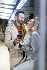 Happy man and woman standing with mobile phone - WPEF07400