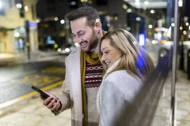 Spiegelung eines Mannes und einer Frau, die ein Smartphone benutzen - WPEF07401