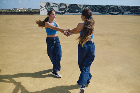 Happy girls holding hands and playing on sunny day - ASGF03610