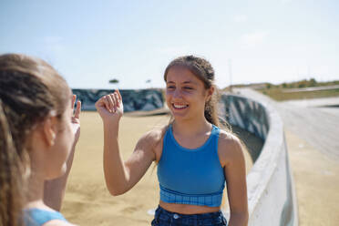 Happy girls playing together in skateboard park - ASGF03620