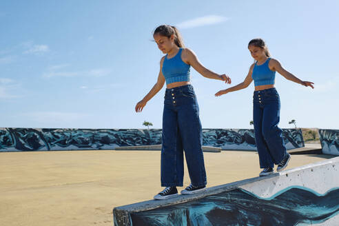 Schwestern, die auf einer Mauer im Skateboardpark laufen - ASGF03622