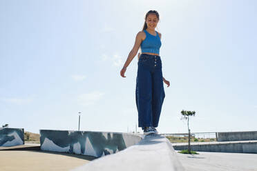 Happy girl walking on wall in front of sky - ASGF03625