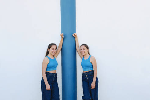 Lächelnde Schwestern stehen vor einer weißen Wand - ASGF03635