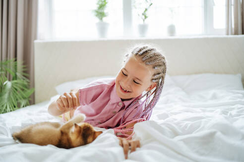 Lächelndes Mädchen spielt mit rotem Kätzchen auf dem Bett - MDOF01218