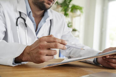 Doctor examining medical report at desk in clinic - OSF01595