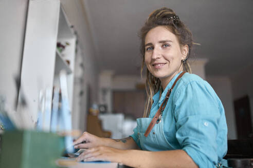 Smiling craftswoman sitting in workshop - ANNF00256