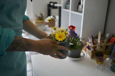 Frau arrangiert Blumentopf auf Tisch bei Workshop - ANNF00269