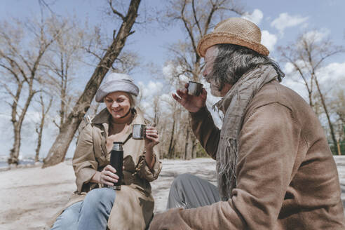 Couple enjoying tea sitting at beach - YTF00892