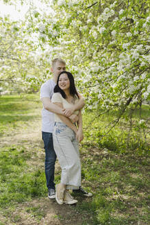 Junges Paar umarmt sich unter einem Baum im Park - SEAF01930