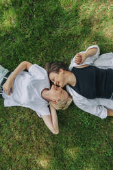 Lesbian couple kissing lying on grass - VSNF01020