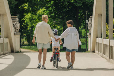 Lesbisches Paar, das mit seiner Tochter auf dem Fußweg im Park Rad fährt - VSNF01023