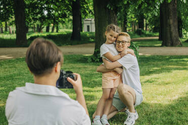 Frau fotografiert Mutter, die ihre Tochter im Park umarmt - VSNF01044