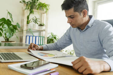 Businessman reading business strategy at desk in office - OSF01612