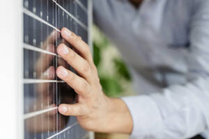 Hand eines Geschäftsmannes berührt Solarpanel im Büro - OSF01615