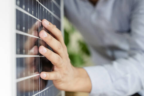 Hand of businessman touching solar panel at office - OSF01615
