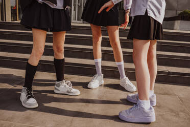 Female friends wearing shoes standing near steps - MDOF01252