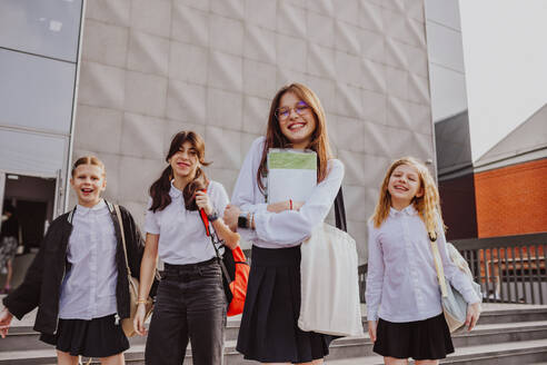 Schoolgirls wearing uniforms standing in front of school building - MDOF01256