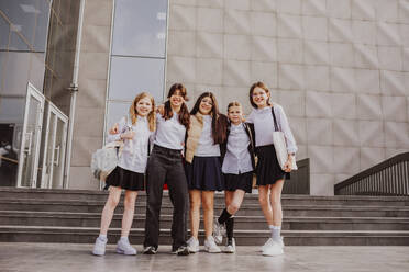 Schulmädchen in Uniformen vor einem Schulgebäude - MDOF01263